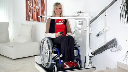 Eine junge Dame benutzt mit ihrem Rollstuhl den Plattformtreppenlift DELTA