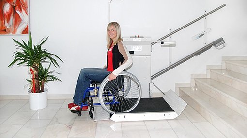 Eine junge Dame benutzt mit ihrem Rollstuhl den Plattformtreppenlift